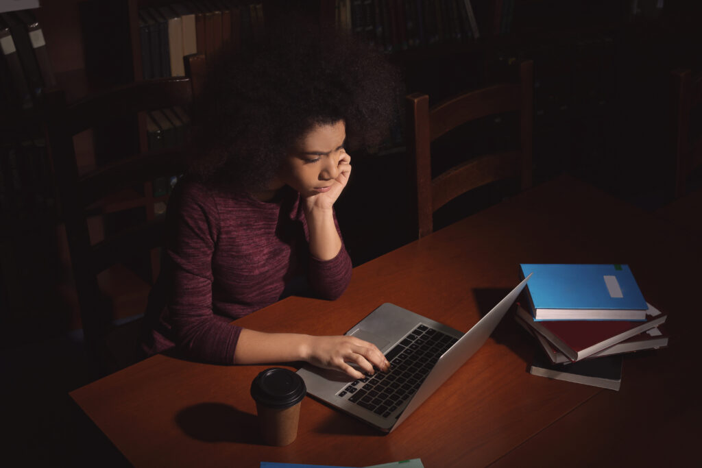 A student in the library on the laptop working on school assignment or studying